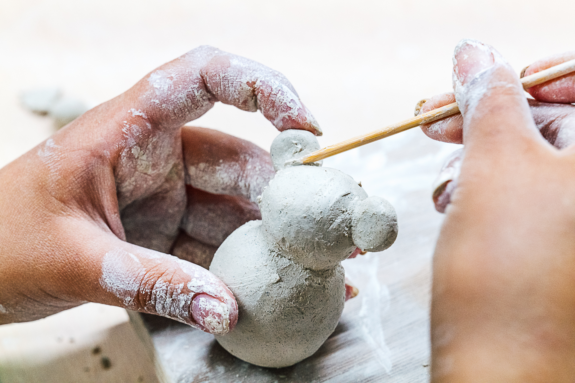 Childs hands shaping animal shape using white coloured clay.