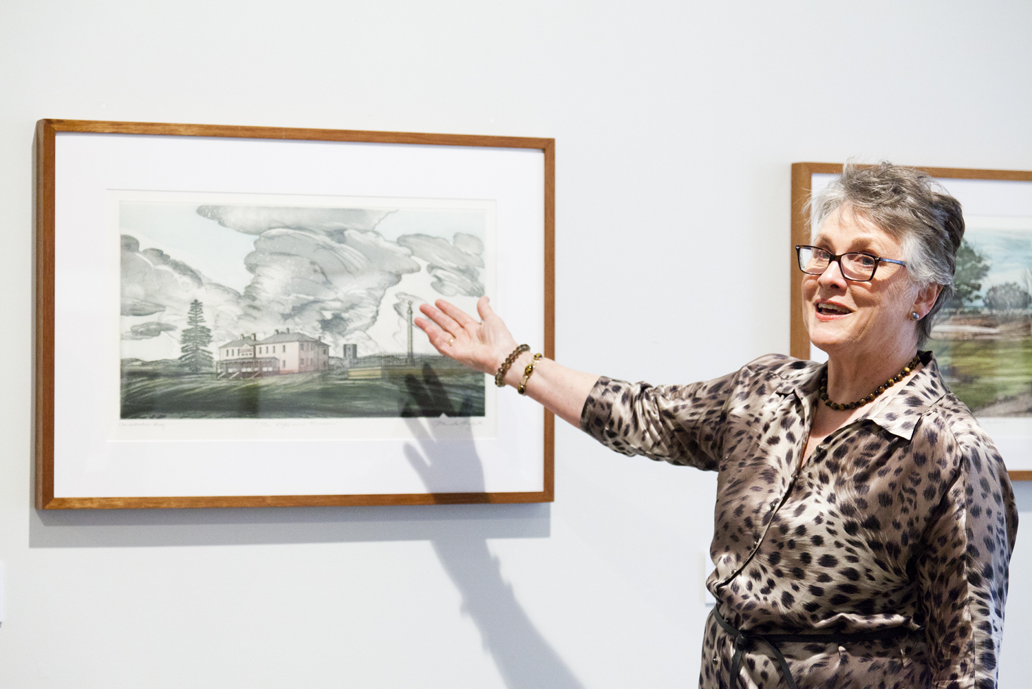 Artist Pamela Griffith standing in front of a framed print in a gallery space.
