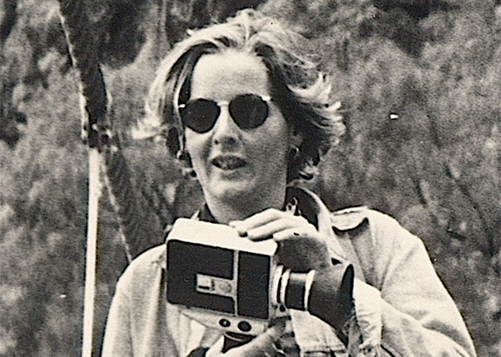 Vintage black and white photograph of a woman in sunglasses holding a video camera.