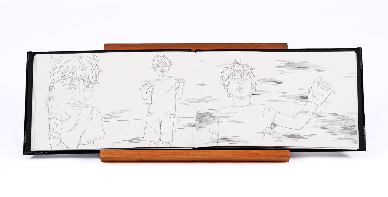 A landscape format book on a timber stand open to a double-page spread showing three line drawings of people.