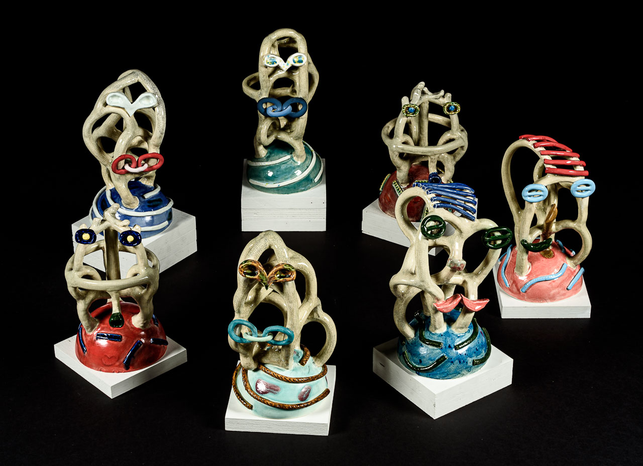 Seven small looping ceramic sculptures with colourful accents and bases.