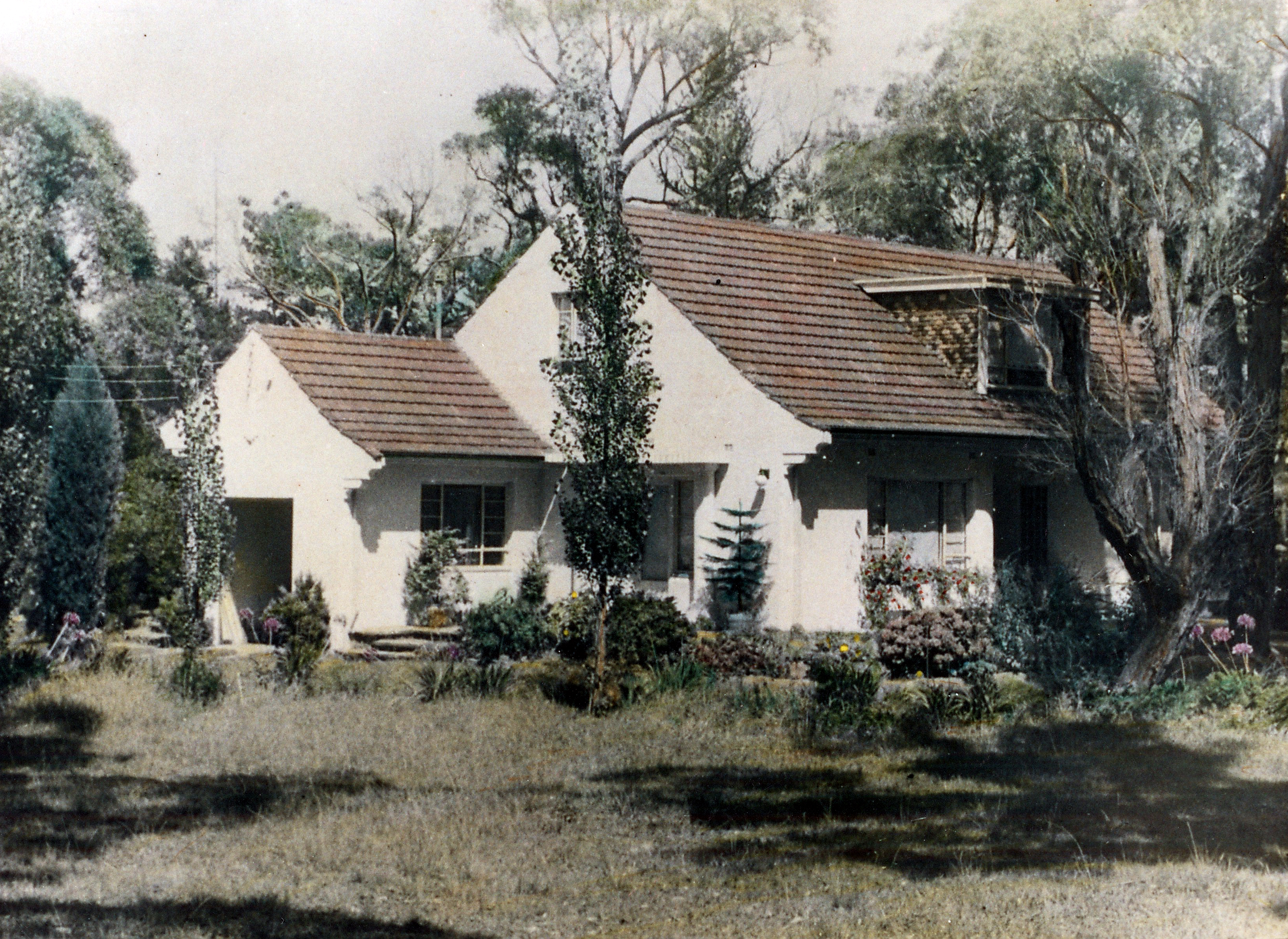 A faded photograph of the original Hazelhurst cottage, surrounded by an overgrown garden.