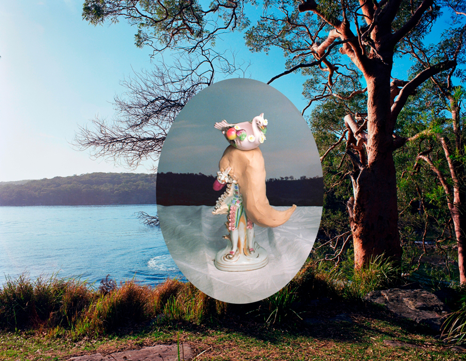 A photograph of a lake with an oval photograph of a ceramic figure placed in the centre.