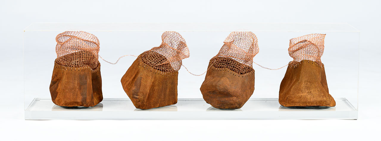Four bag like sculptures that lool like rusted metal on the bottom and are woven wire on the top.