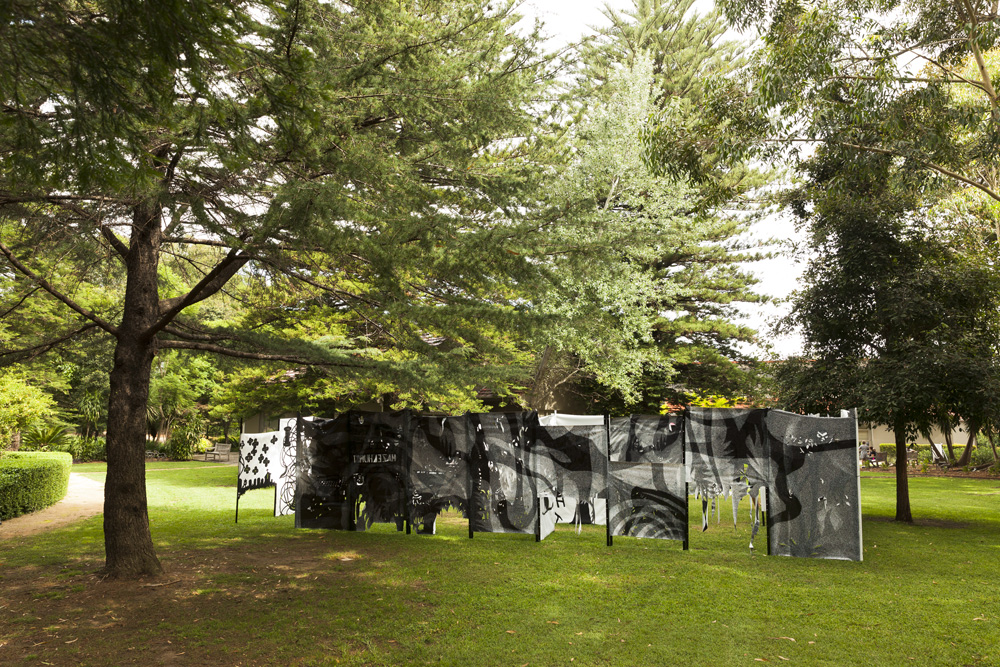 A large weblike structure of panels featuring flat shadow puppet shapes in the Hazelhurst Gardens.