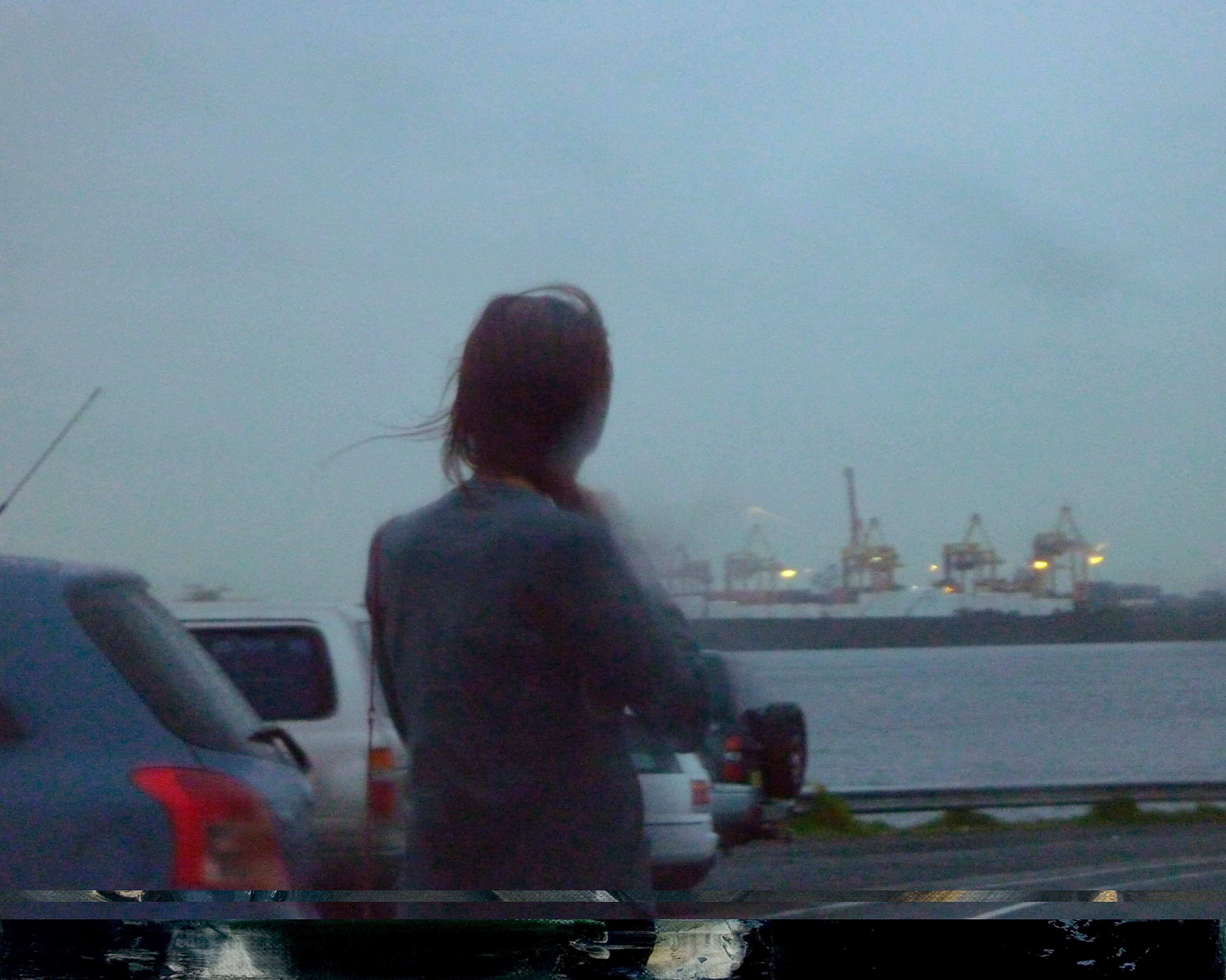Video still of a woman with long hair looking out over modern day Port Botany.