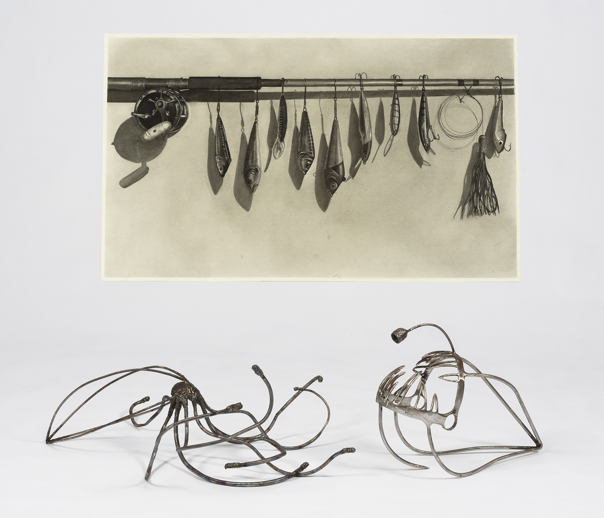 A charcoal drawing and two metal sculptures that resemble an octopus and an angler fish.