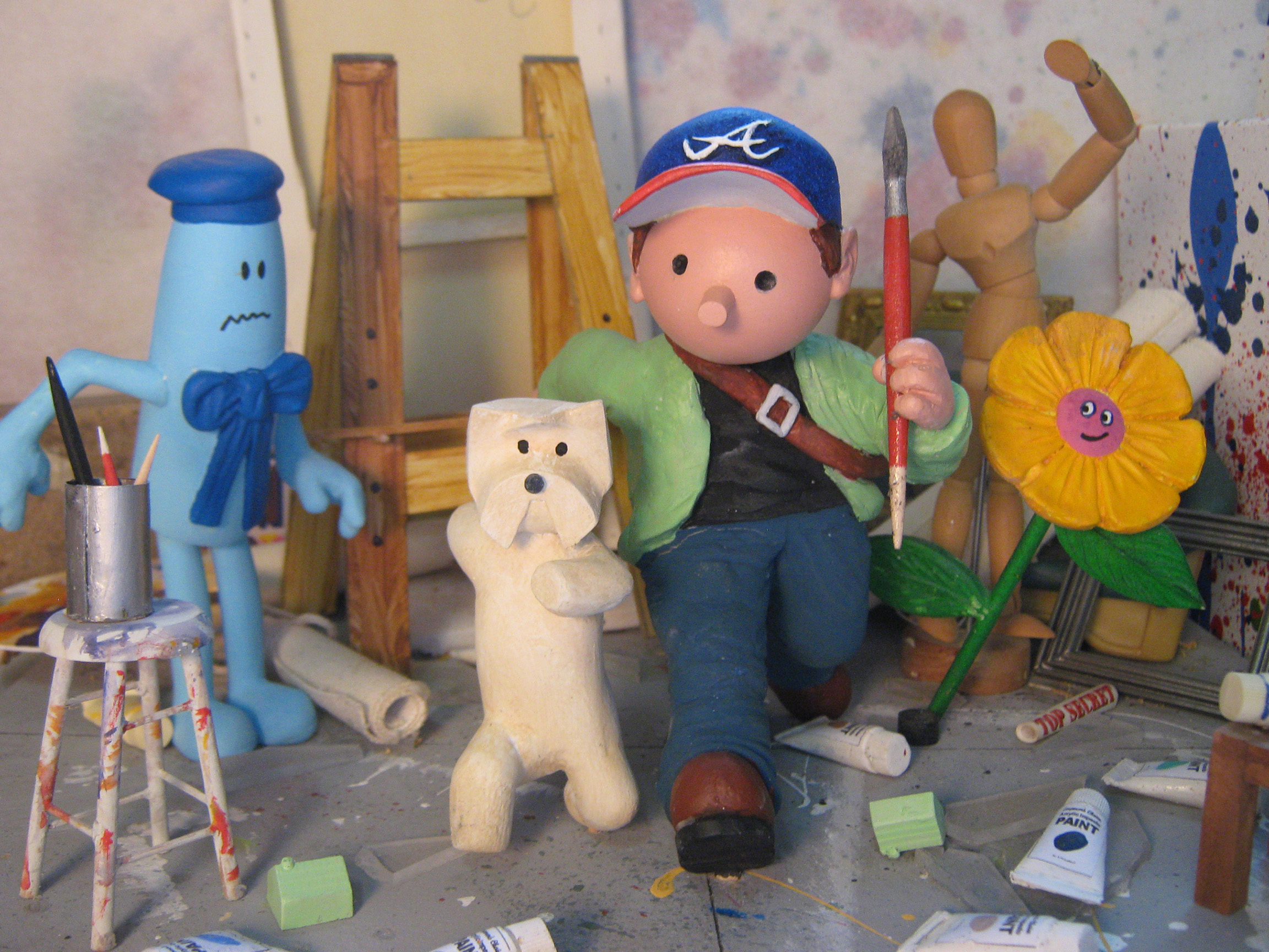 A small, sculpted scene of a character and his dog running through an art studio by artist Alisdair Macintyre.