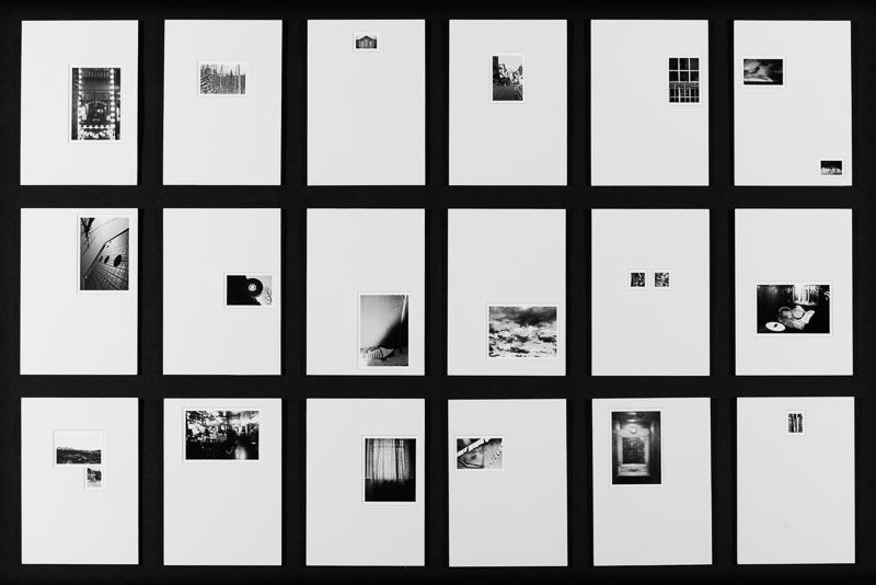 A grid of 18 black and white photographs of various sizes, each is mounted in a different position on a white background.
