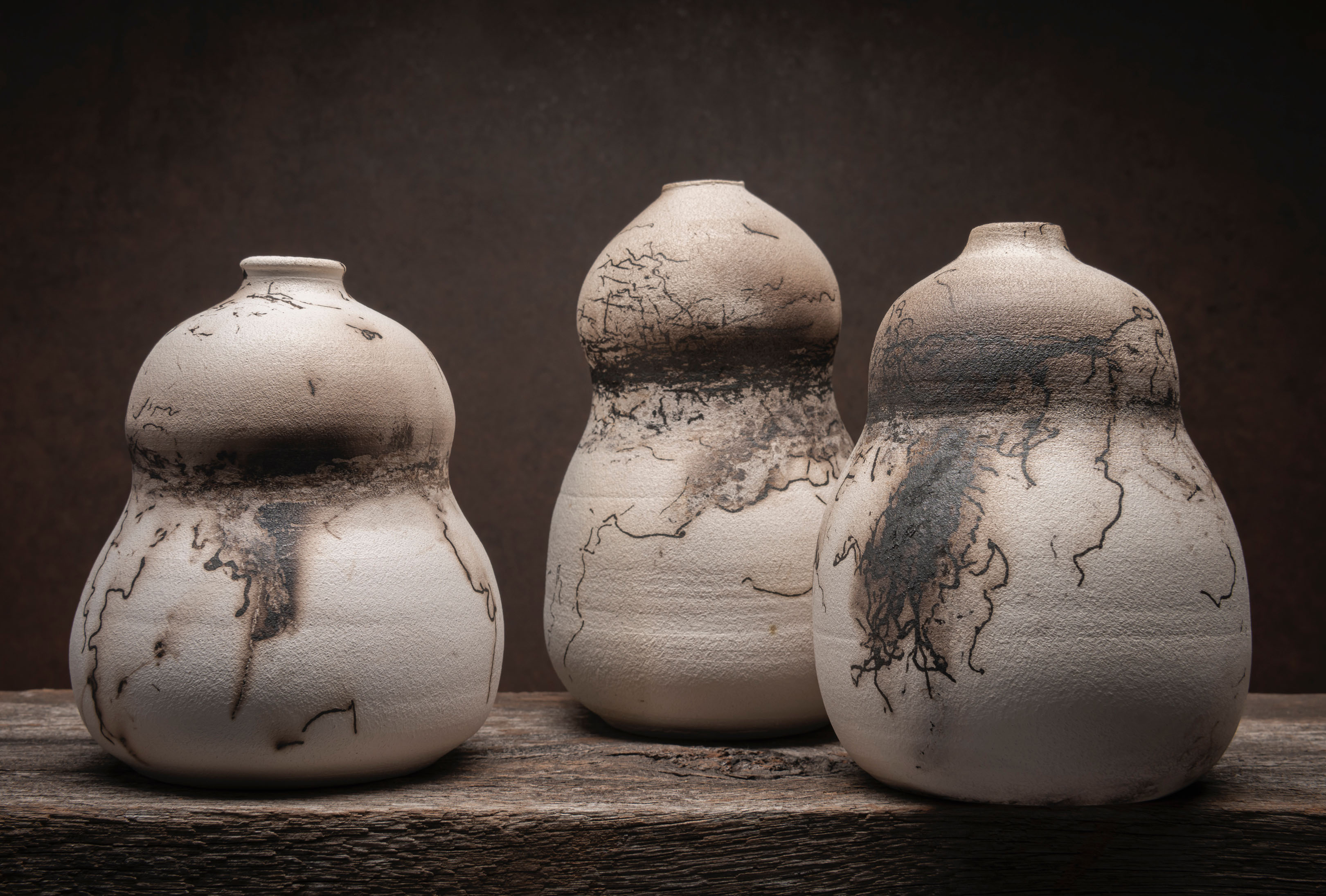 Three white clay pots with dark brown patterning in the surface.